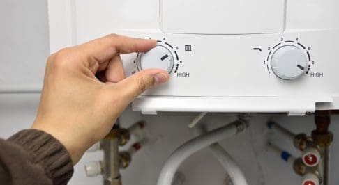 person turning knob on water heater